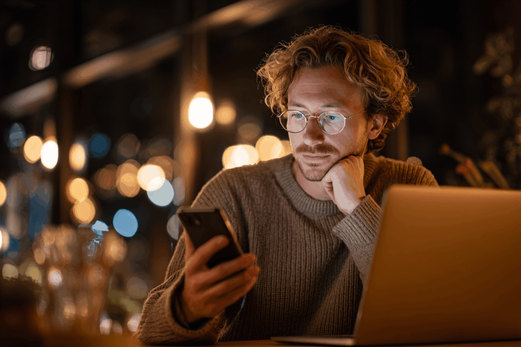 Мужчина проверяет подозрительное SMS-сообщение на предмет фишинга, сравнивая ссылку с официальным сайтом